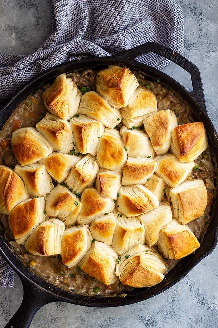 This easy Skillet Beef Pot Pie makes a great weeknight meal when you are craving comfort food. It's filled with vegetables and ground beef in an easy to make gravy. Topped with store bought or homemade biscuits to complete the dish! #potpie #groundbeef #easyrecipe #beefpotpie