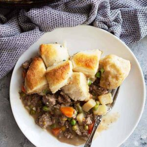 This easy Skillet Beef Pot Pie will please the whole family. It's filled with ground beef and vegetables in an easy homemade gravy. Top with store bought or homemade biscuits for the ultimate comfort food! #potpie #groundbeef #easyrecipe #beefpotpie