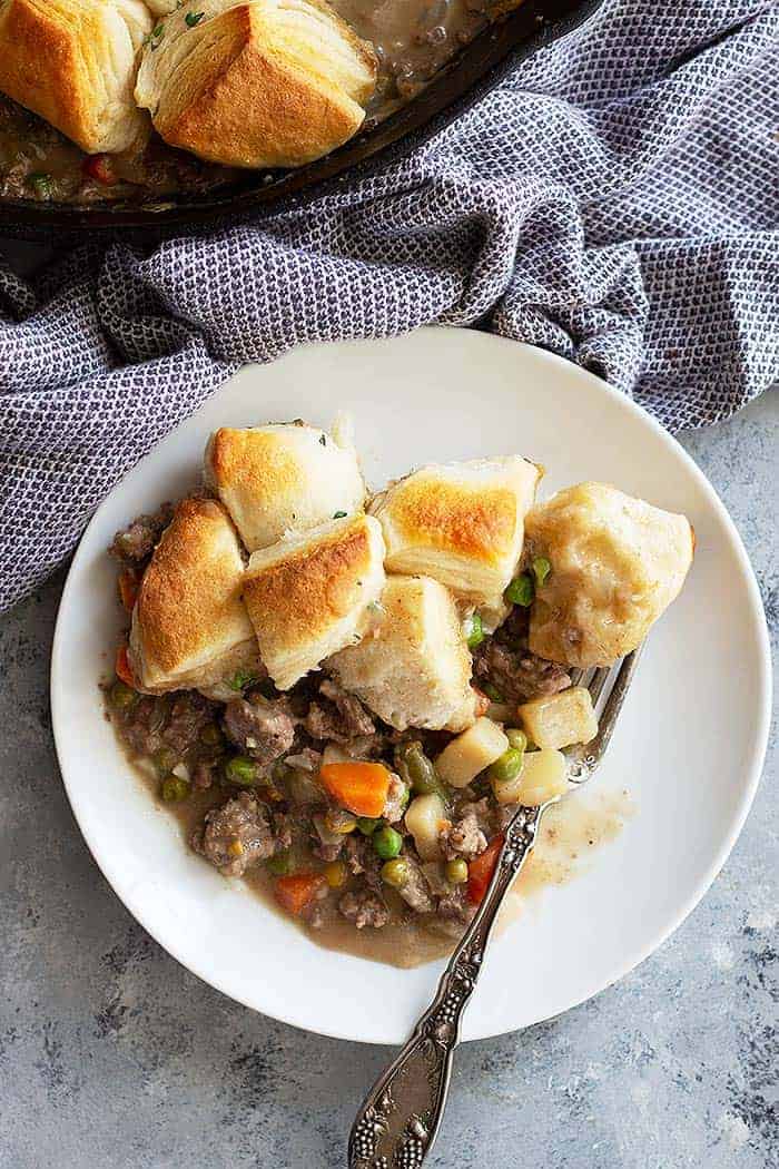 This easy Skillet Beef Pot Pie will please the whole family. It's filled with ground beef and vegetables in an easy homemade gravy. Top with store bought or homemade biscuits for the ultimate comfort food! #potpie #groundbeef #easyrecipe #beefpotpie
