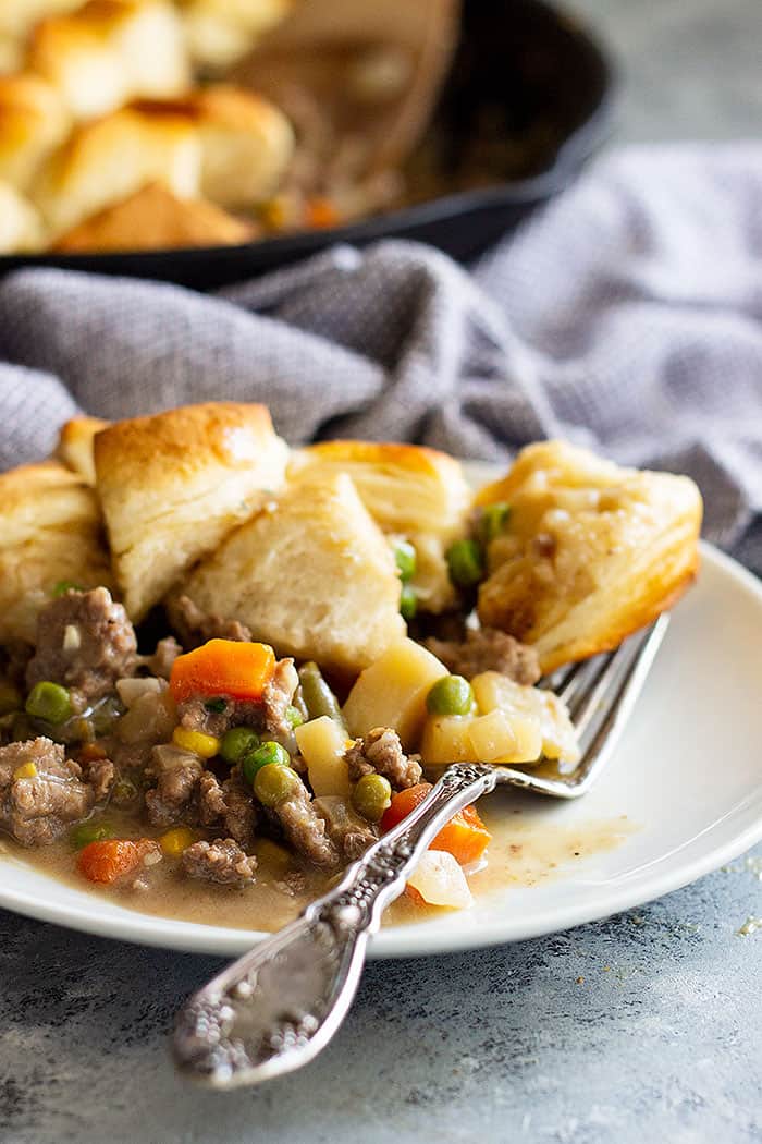 This Easy Skillet Beef Pot Pie Recipe is the ultimate comfort food made easy! It's filled with vegetables in an easy homemade gravy and topped with biscuits. #potpie #groundbeef #easyrecipe #beefpotpie