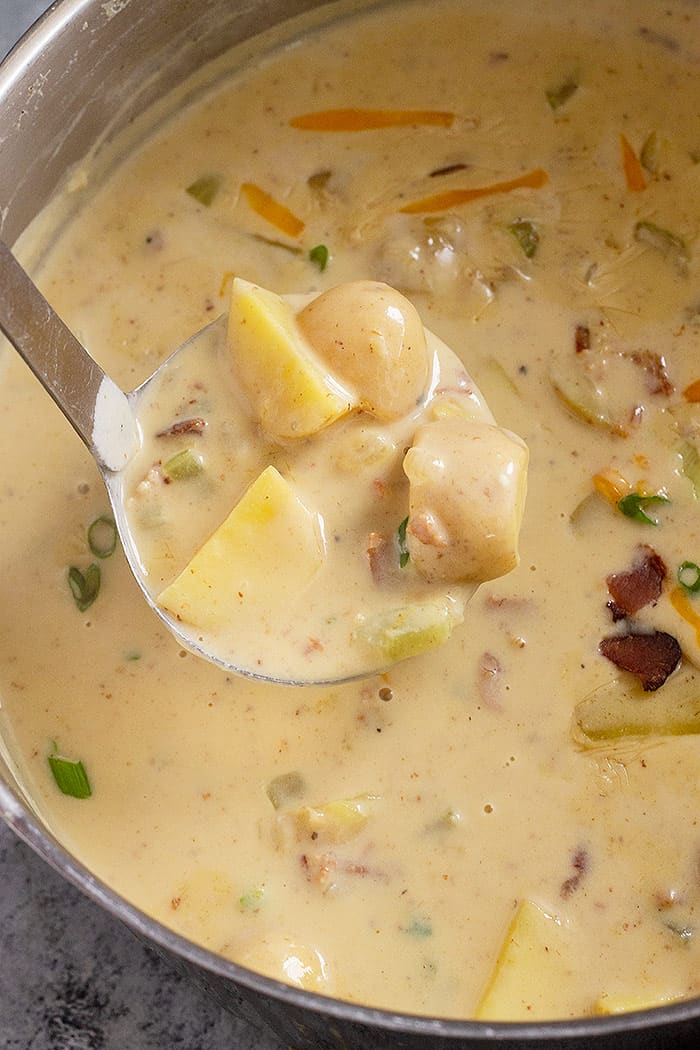Creamy potato soup in a pot with a ladle. 