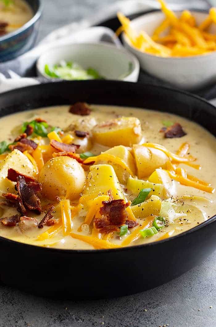 A large bowl of potato soup garnished with cheese, bacon, and green onion. 