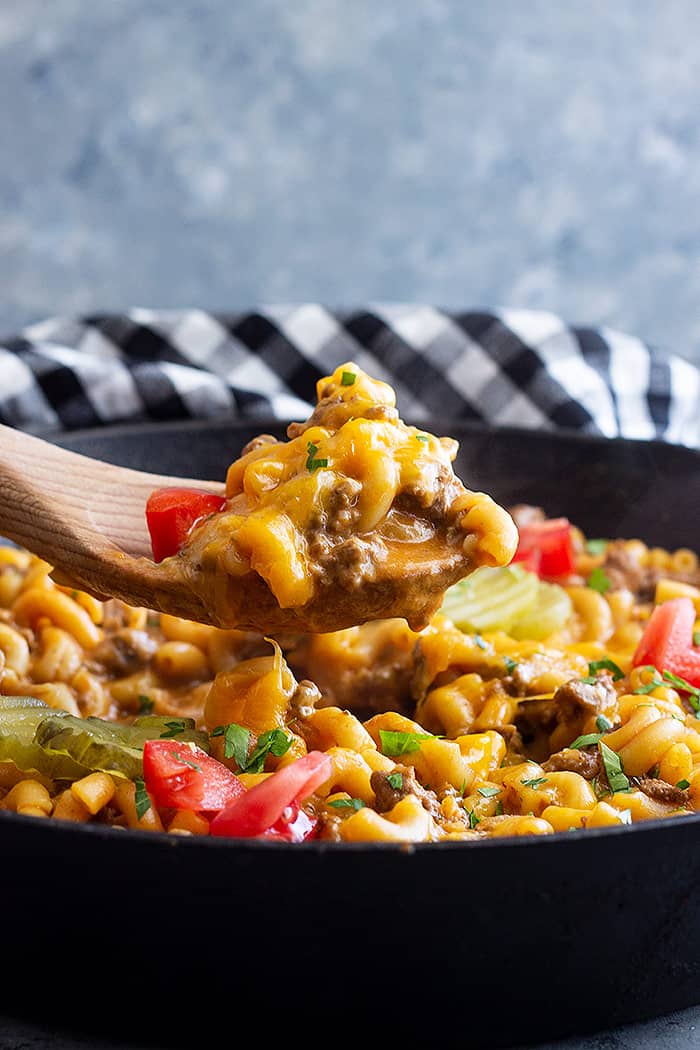 A skillet of cheeseburger pasta with a spoon pulling up a serving. 