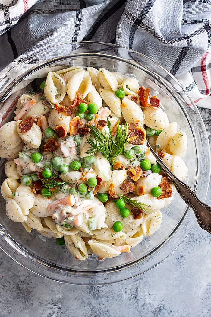 Top down view of pasta salad in a bowl with a large serving spoon.