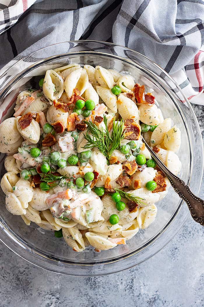 Top down view of pasta salad in a bowl with a large serving spoon. 