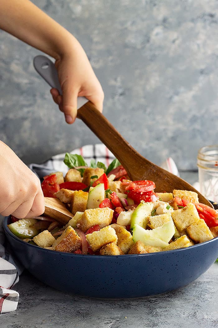 Tossing panzanella salad with mozzarella and a flavorful dressing. 