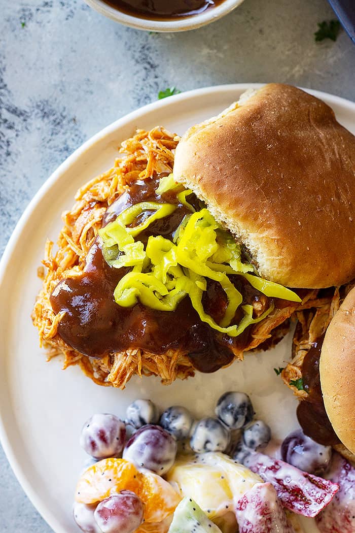 Close up picture of slow cooker bbq chicken on a bun with bbq sauce. 