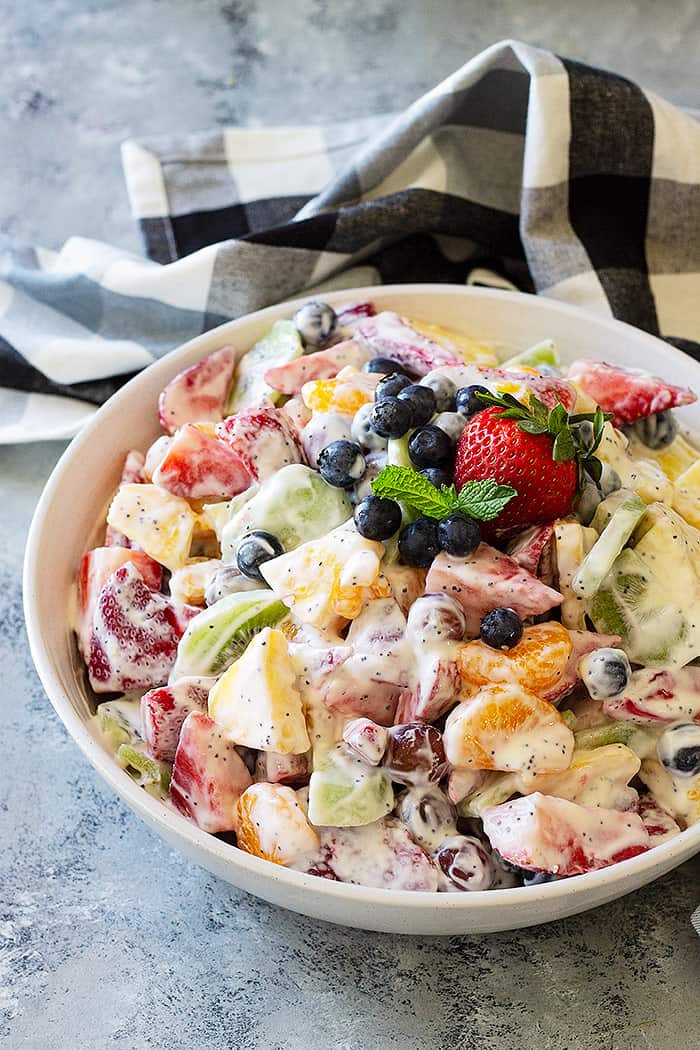 Creamy Fruit Salad mixed and in a large bowl. Garnished with fresh blueberries and mint. 