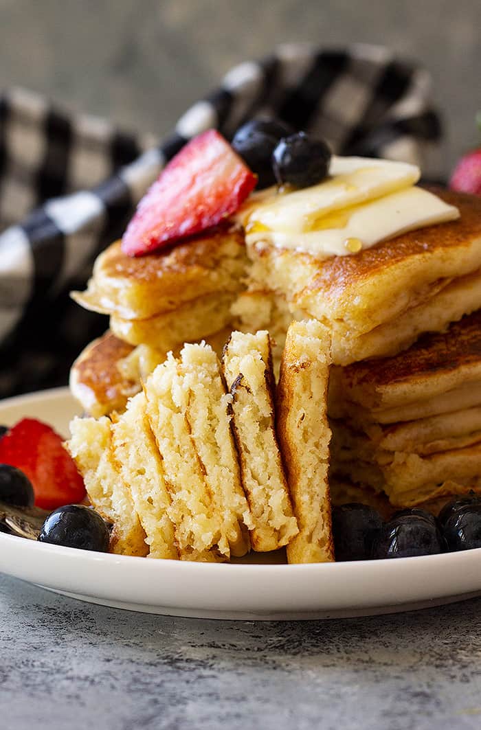 A fork stacked with a big bite of fluffy buttermilk pancakes ready to be eaten. 