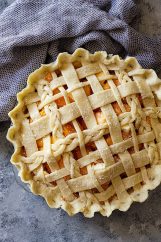 Top down view of a peach pie with an all butter crust lattice top.