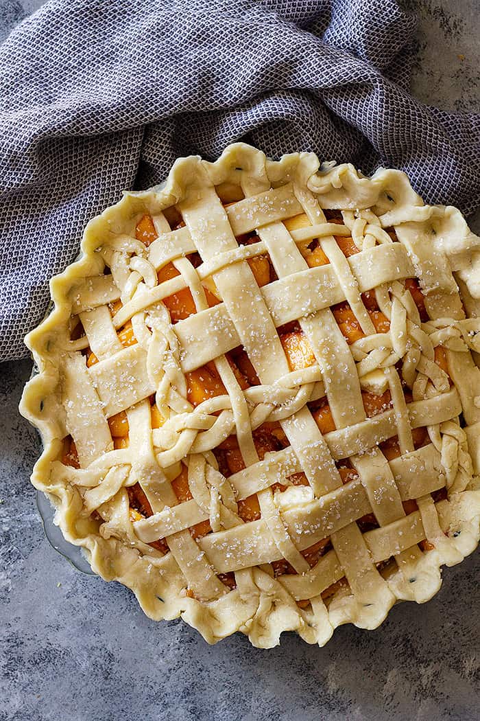 Top down view of a peach pie with an all butter crust lattice top. 