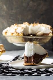 Slice of chocolate meringue pie on a plate with a bite taken out.