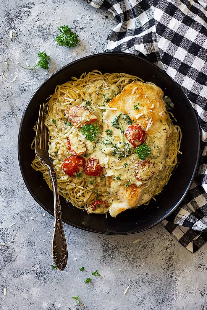 Bowl filled with pasta and topped with creamy tuscan chicken.