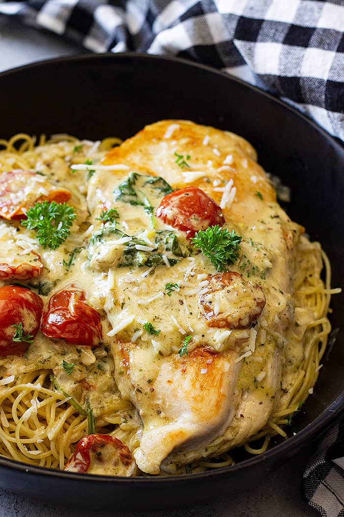 Close up of Creamy Tuscan Chicken in a bowl on top of pasta. 