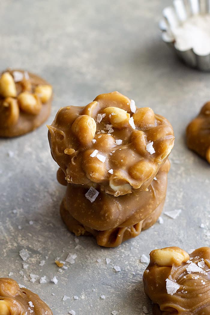 A stack of easy peanut pralines with sea salt sprinkled around them.