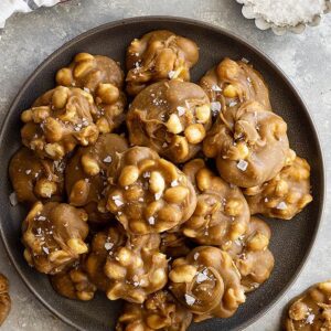 Top down view of easy peanut pralines on a plate and flaky sea salt scattered.