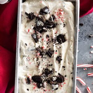 No Churn Peppermint Ice Cream in a pan decorated with chopped peppermints and oreos.
