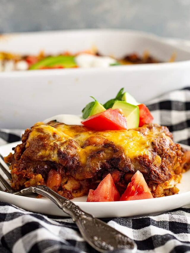 A slice of Mexican Casserole on a white plate with a fork.