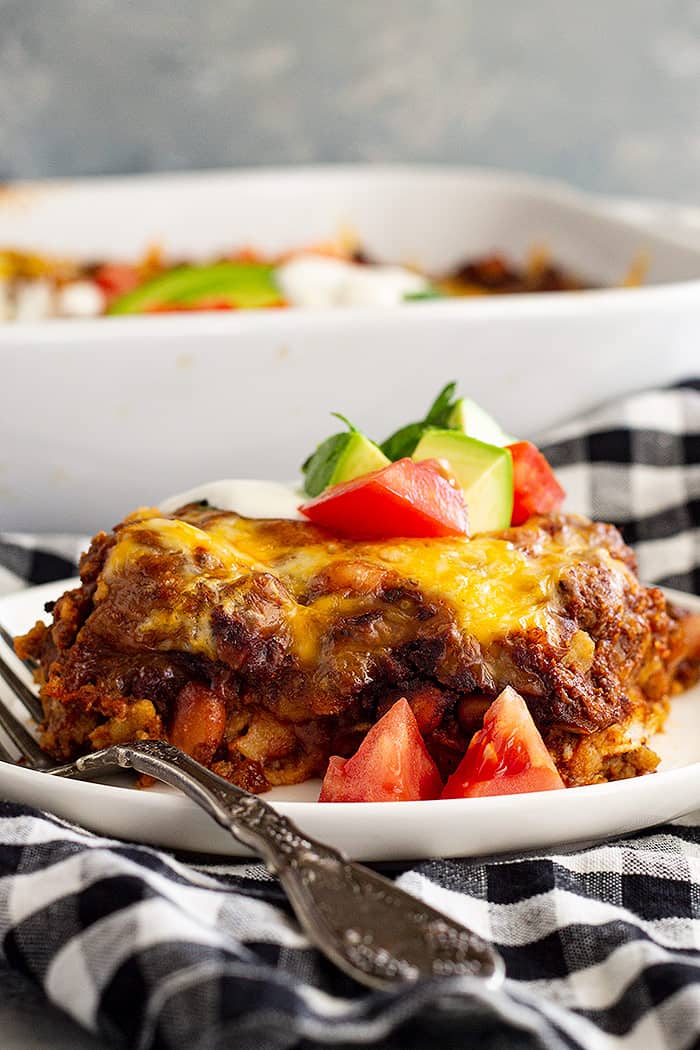 A slice of Mexican Casserole on a white plate with a fork.