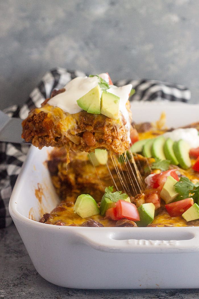 A spatula pulling up a large piece of Mexican Casserole with a nice cheese pull.