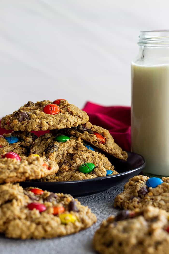 Monster cookies on a plate with a glass of milk. 