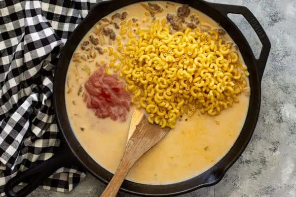 Overhead view of skillet with pasta, tomato sauce, broth, and milk added.