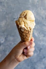 A child's hand holding up an ice cream cone.