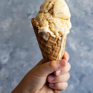A child's hand holding up an ice cream cone.
