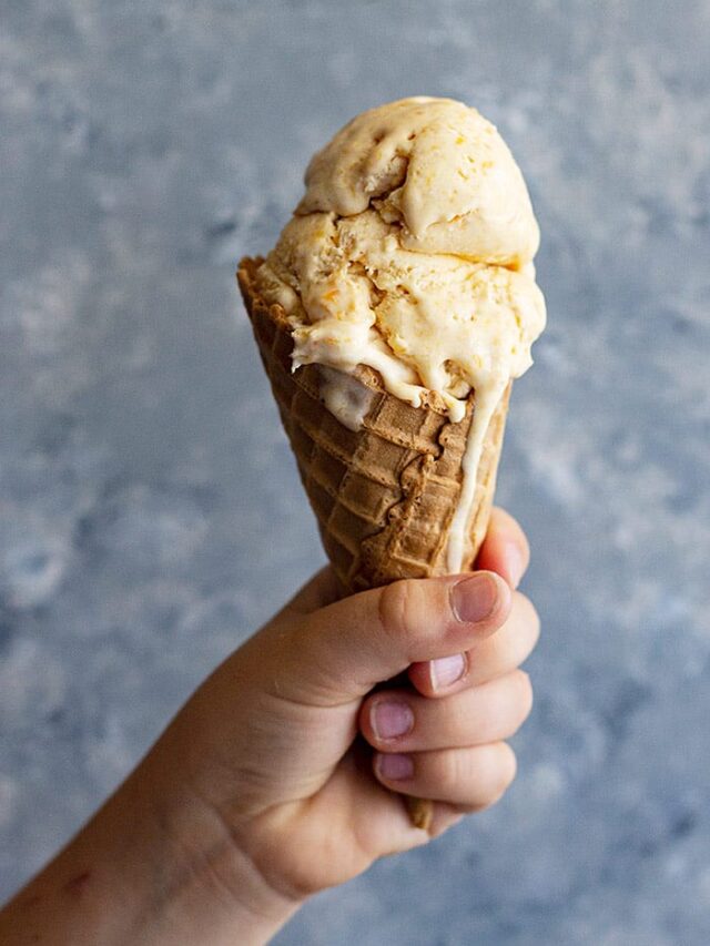 A child's hand holding up an ice cream cone.