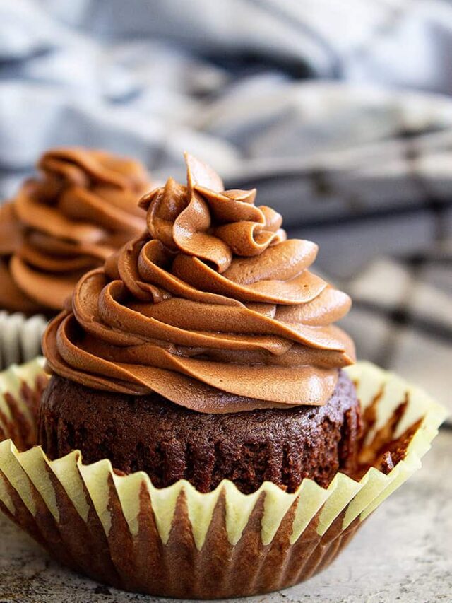 Frosting piped in a swirl on top of a chocolate cupcake.