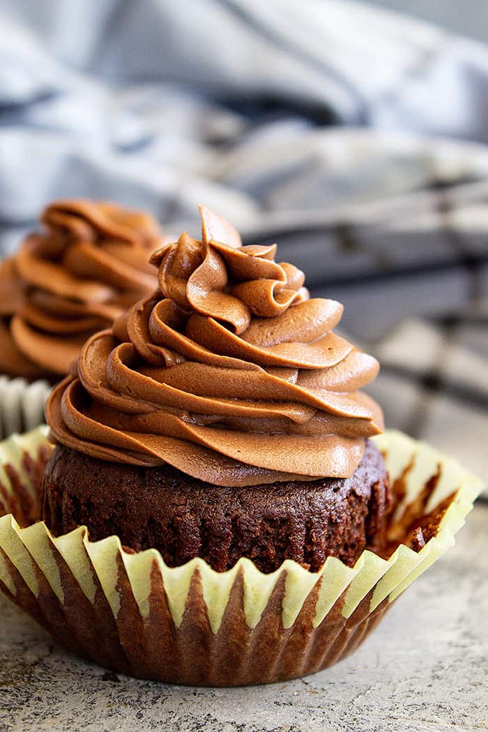 Frosting piped in a swirl on top of a chocolate cupcake.