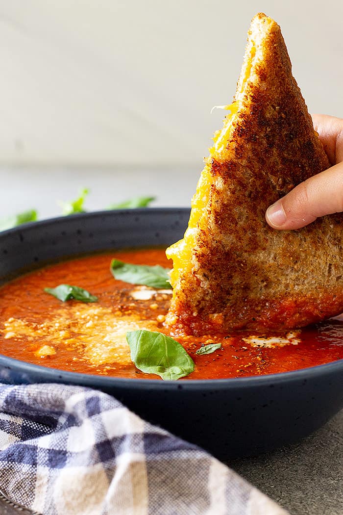 Dipping a grilled cheese into a bowl of hot soup.