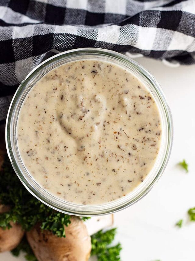 Overhead view of condensed soup in a jar. Black and white checkered napkin, mushrooms, and parsley decorate around the jar.