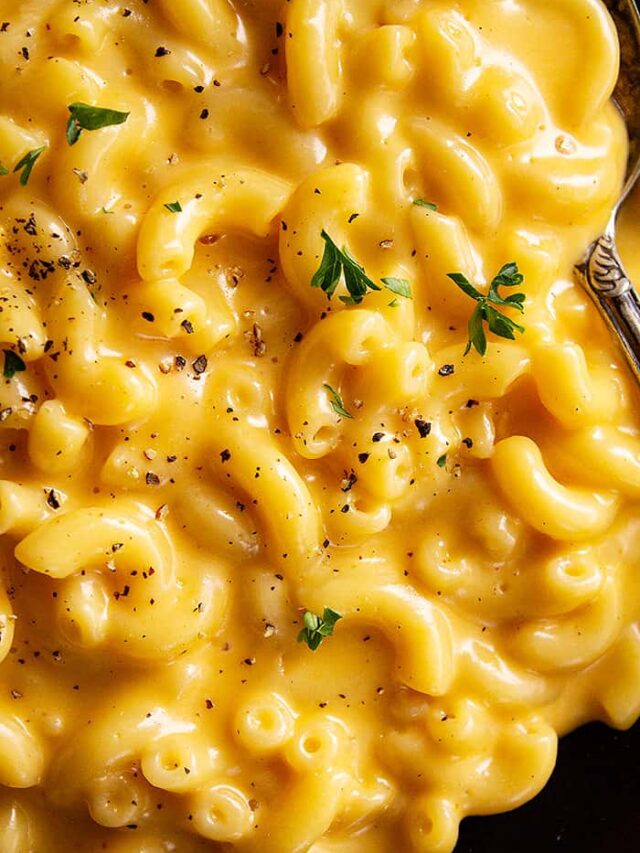 A close up of ultra creamy and cheese mac and cheese sprinkled with black pepper and a little parsley.