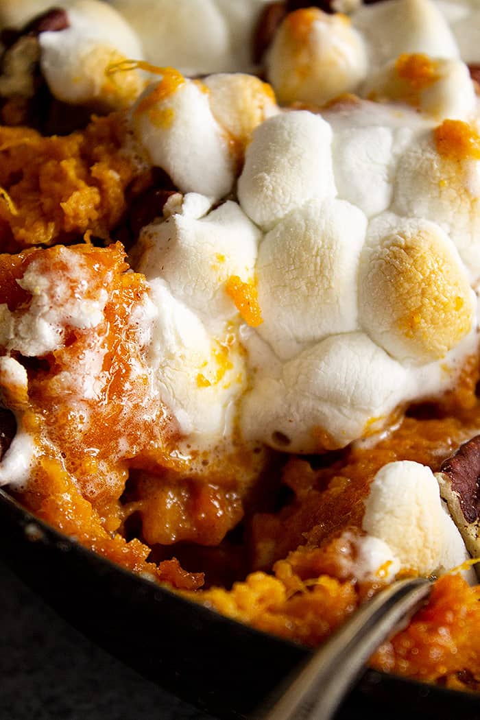 A close up of a scoop of sweet potato casserole take out and you can see the melty marshmallows.