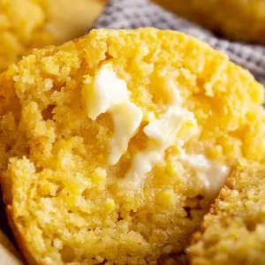 A close up of a muffin cut in half with butter melting on it.