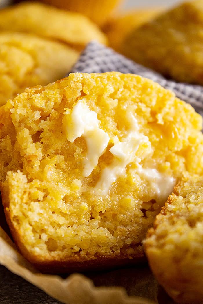 A close up of a muffin cut in half with butter melting on it.