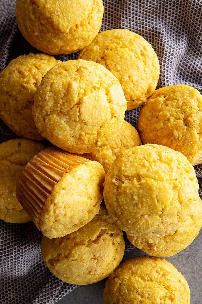 Overhead view of muffins piled high in a group with a blue towel around them.