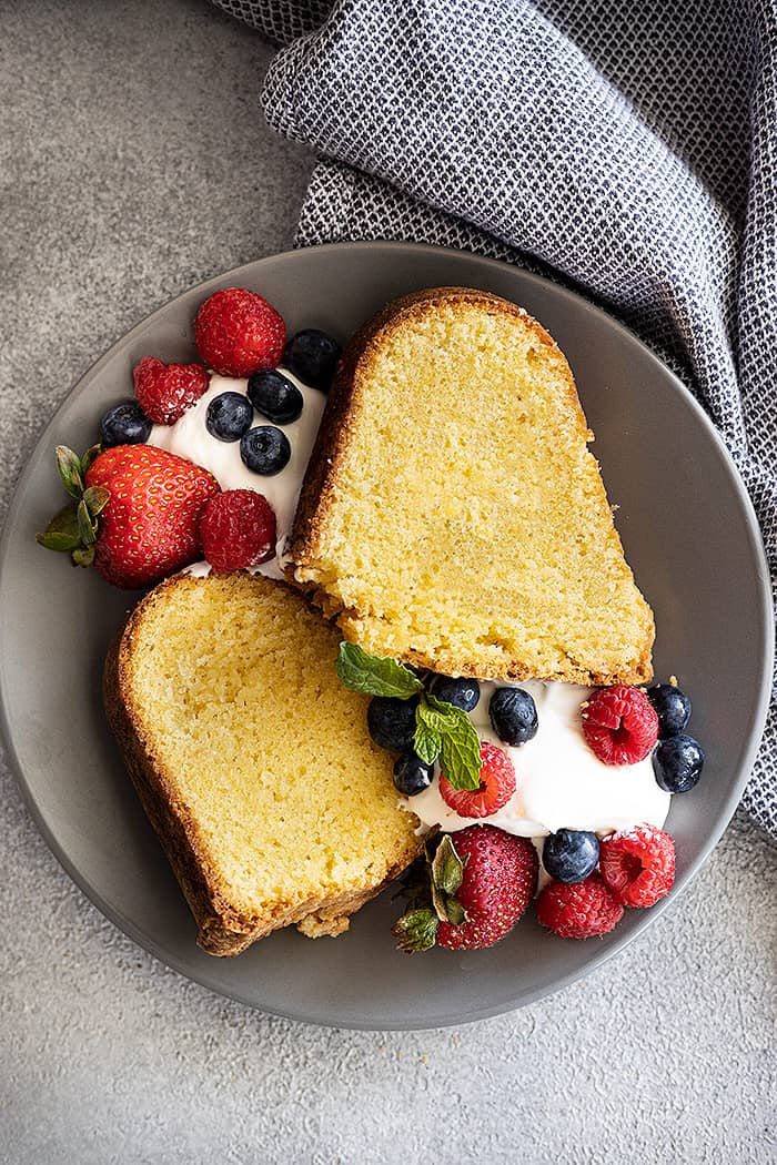 Overhead view of 2 slices of pound cake with whipped cream and fresh berries on the side. 