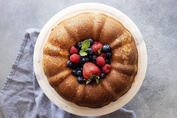 Overhead view of pound cake with fresh berries piled high in the middle. 