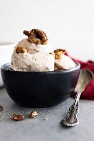 A bowl of cinnamon ice cream topped with candied pecans.