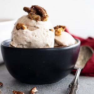 A bowl of cinnamon ice cream topped with candied pecans.