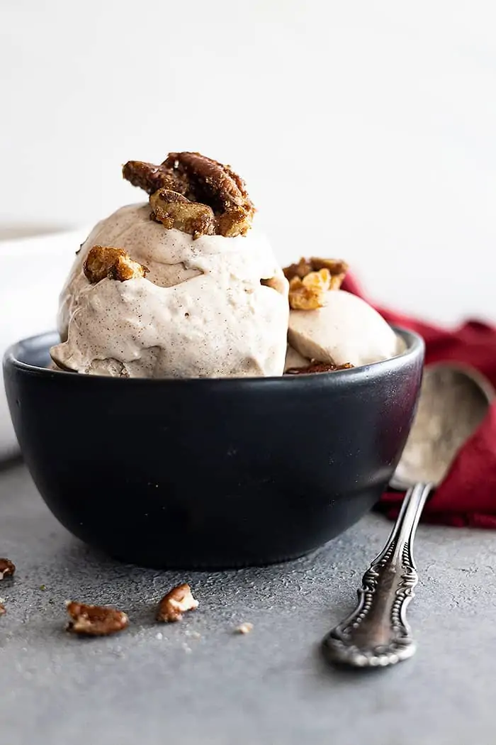 A bowl of cinnamon ice cream topped with candied pecans. 