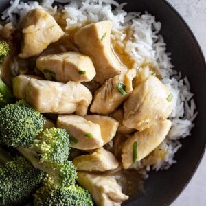 Overhead view of chinese lemon chicken in a bowl over white rice and a side of steamed broccoli.