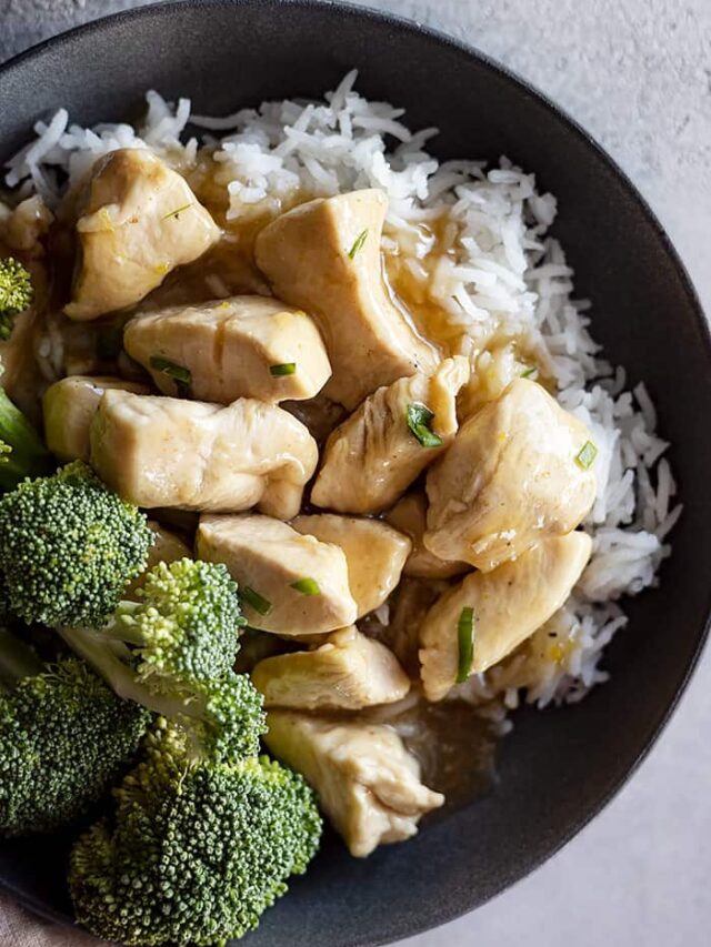 Overhead view of chinese lemon chicken in a bowl over white rice and a side of steamed broccoli.