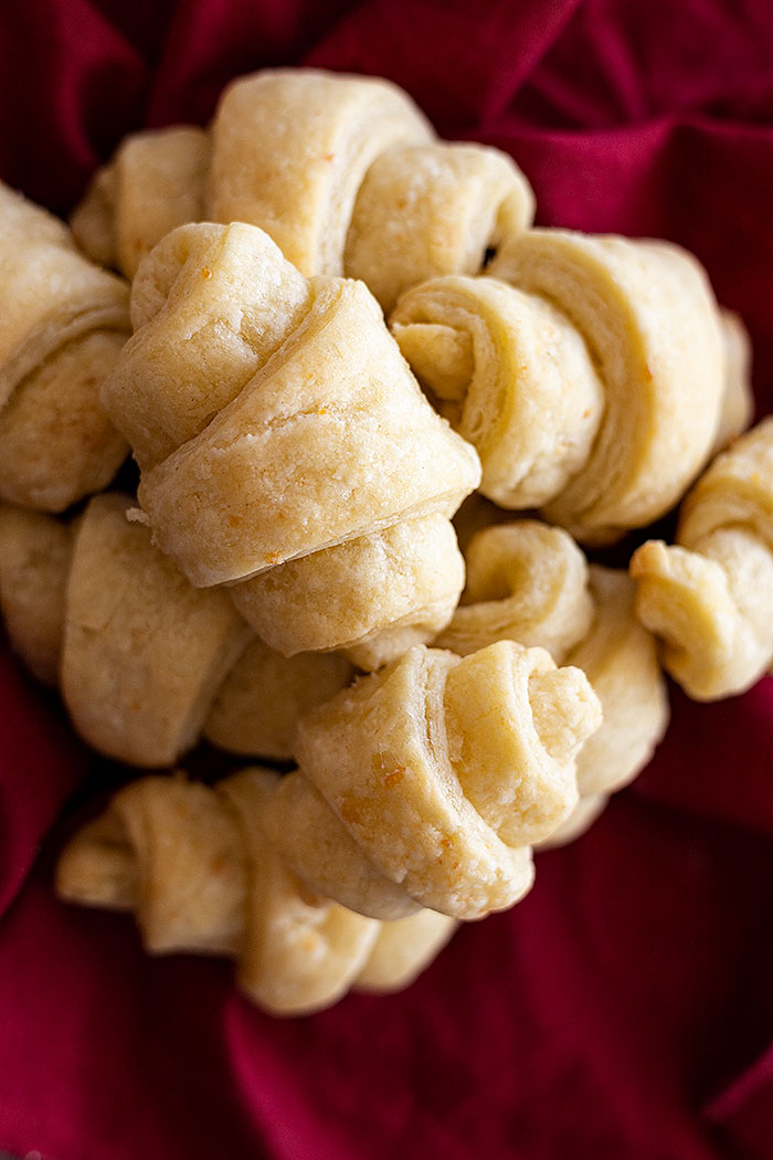 Overhead view of several rolls stacked on top of one another on top of a dark red cloth napkin.