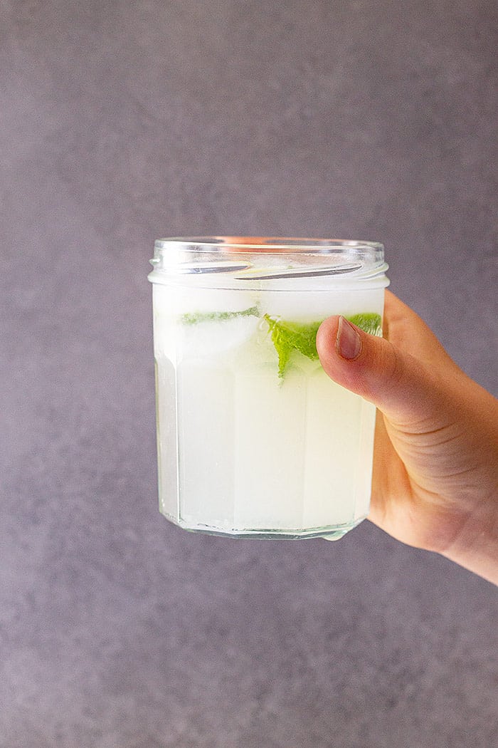 A glass of fresh limeade raised ready to drink.