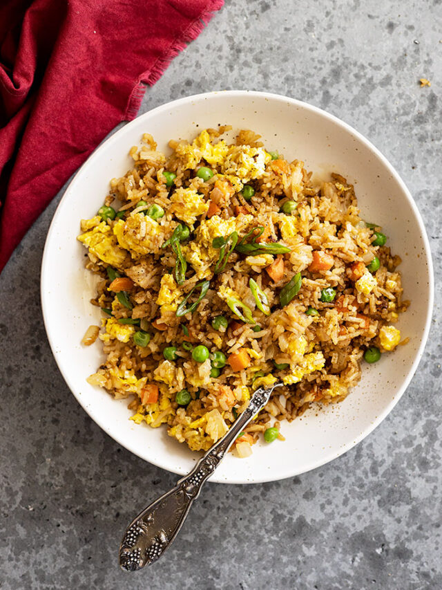 Overhead view of fried rice in a bowl garnished with green onion.