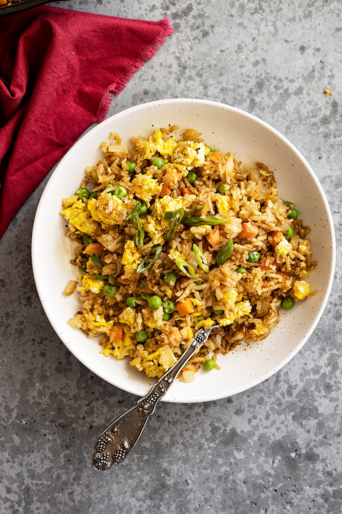 Overhead view of fried rice in a bowl garnished with green onion.