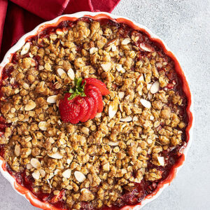 Overhead view of strawberry crisp fresh from the oven with a fresh strawberry fanned out on top for garnish.
